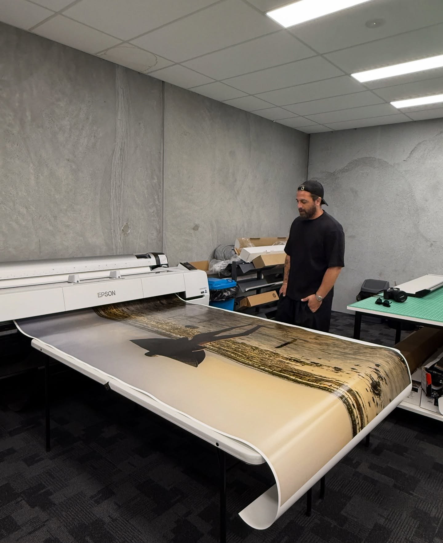 Jude Cohen in the print studio, beside a large print coming off the printer